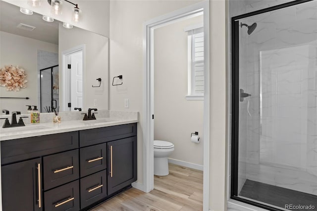 bathroom with double vanity, a sink, a stall shower, and toilet