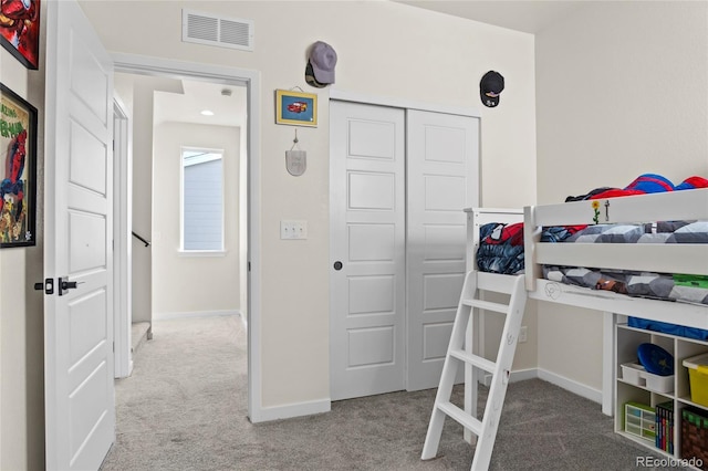 carpeted bedroom featuring baseboards, visible vents, and a closet