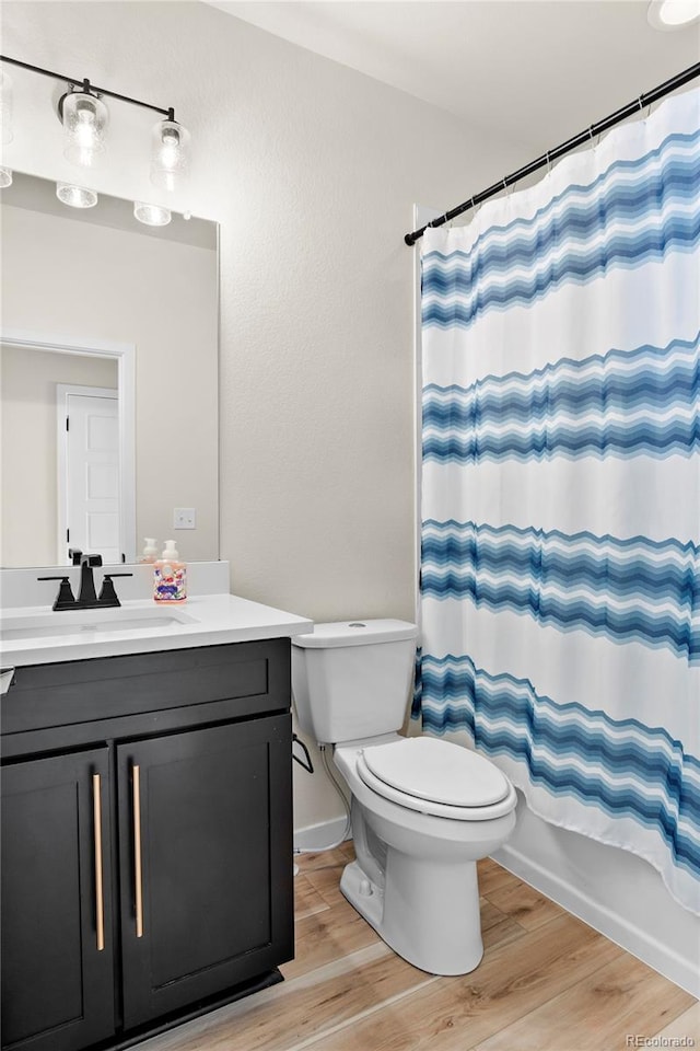 full bath featuring vanity, shower / bathtub combination with curtain, wood finished floors, and toilet