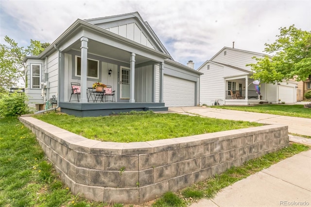 462 Chelan St, Golden, CO 80401 - view of front of property with a porch, board and batten siding, concrete driveway, a garage, and a front lawn