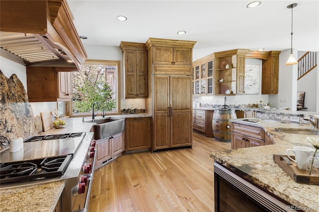 kitchen with a sink, custom range hood, light wood-style flooring, high end stove, and recessed lighting