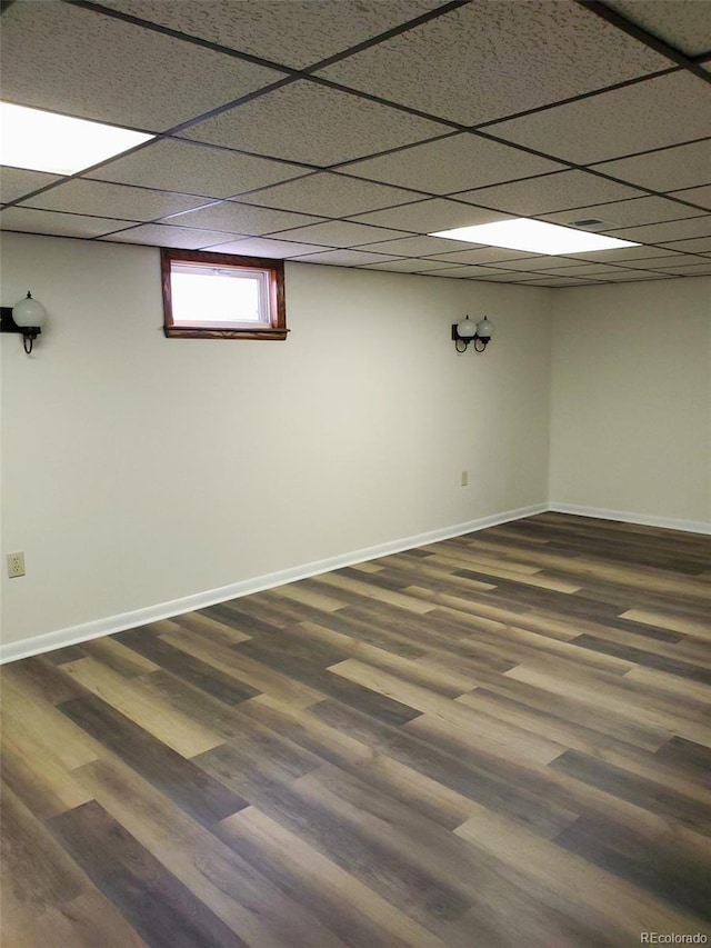 609 S 1st Ave, Brighton, CO 80601 - below grade area featuring dark wood-type flooring, baseboards, and a paneled ceiling