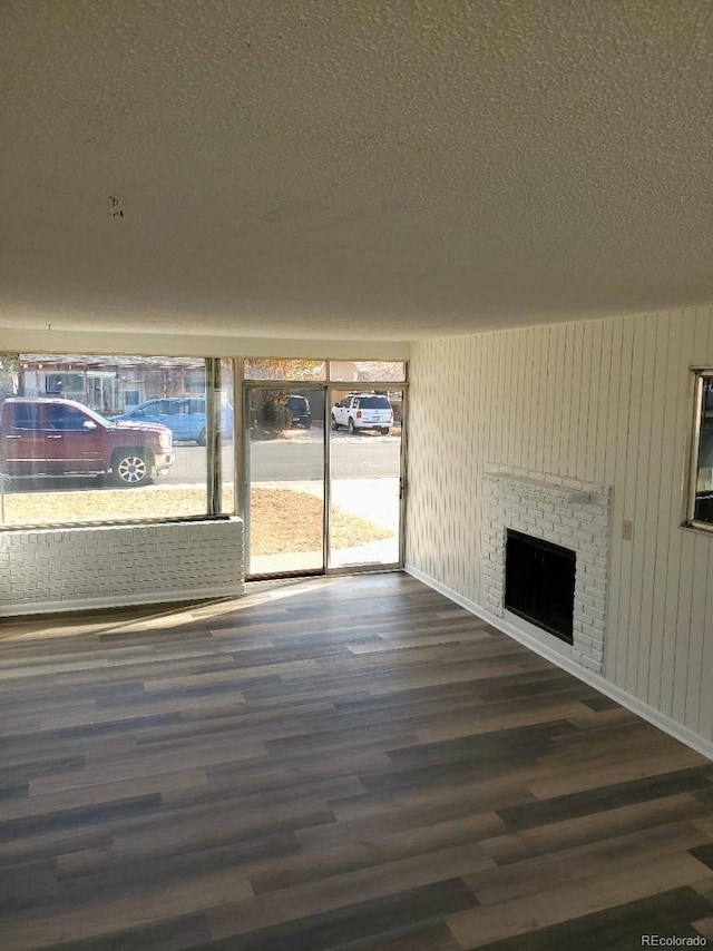 609 S 1st Ave, Brighton, CO 80601 - unfurnished living room with wood finished floors, a brick fireplace, and a textured ceiling