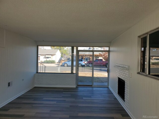 609 S 1st Ave, Brighton, CO 80601 - empty room with a textured ceiling, wood finished floors, a fireplace, and baseboards