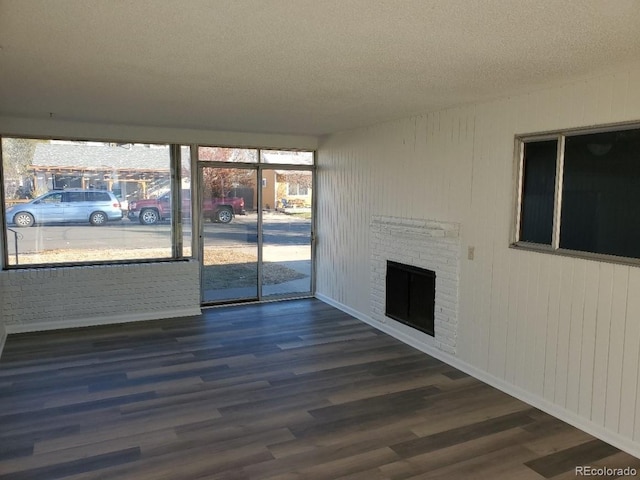 609 S 1st Ave, Brighton, CO 80601 - unfurnished living room featuring a textured ceiling, wood finished floors, a fireplace, and baseboards