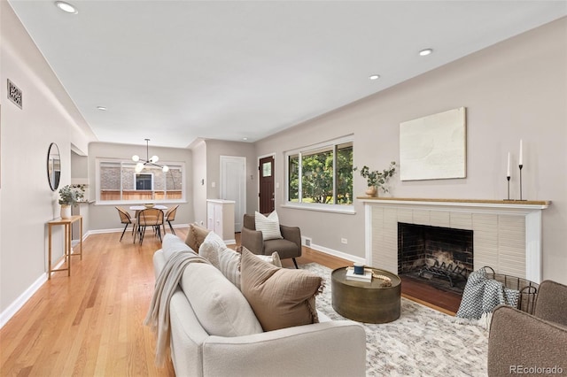 2880 N Glencoe St, Denver, CO 80207 - living room with light wood finished floors, a brick fireplace, recessed lighting, and a chandelier