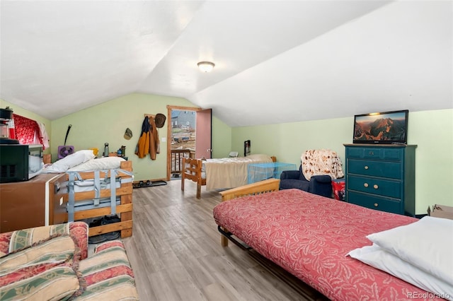 bedroom with light wood-type flooring and vaulted ceiling