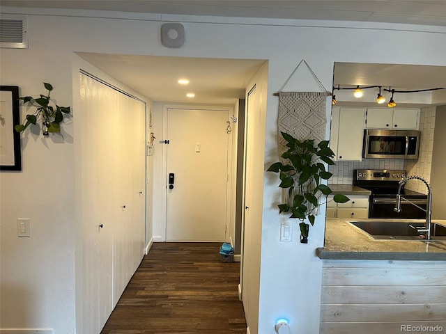 kitchen with dark wood-style flooring, a sink, visible vents, appliances with stainless steel finishes, and tasteful backsplash