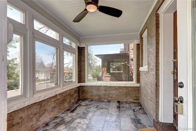 unfurnished sunroom featuring brick wall and stone finish flooring
