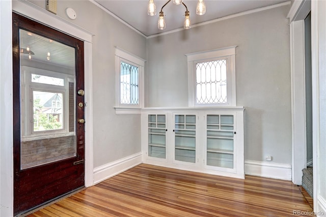 entrance foyer with wood finished floors, ornamental molding, and baseboards