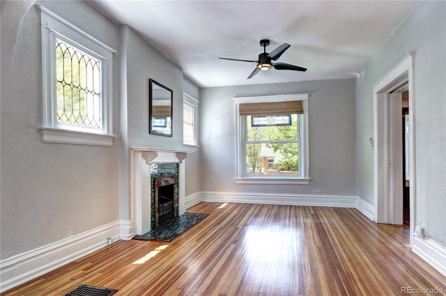 unfurnished living room featuring hardwood / wood-style floors, a fireplace, baseboards, and ceiling fan