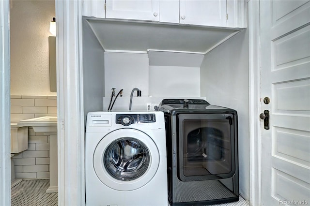 laundry room featuring washer and dryer, cabinet space, tile patterned flooring, and tile walls