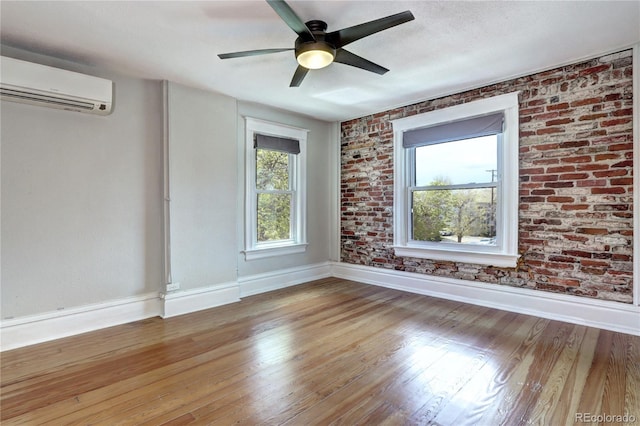 unfurnished room featuring a wall mounted AC, baseboards, light wood-style floors, and a ceiling fan