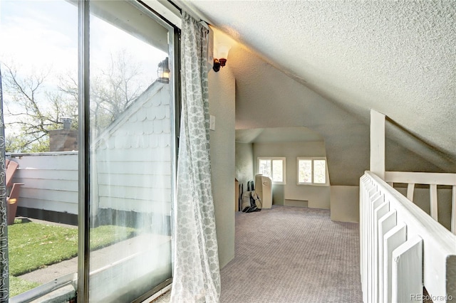 corridor featuring carpet floors, lofted ceiling, a textured ceiling, and an upstairs landing