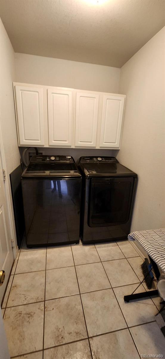 laundry room with independent washer and dryer, cabinets, and light tile patterned flooring