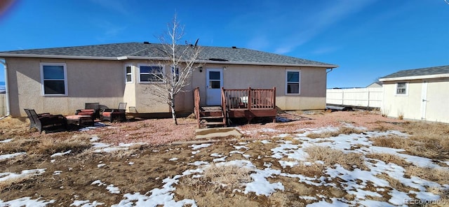 snow covered back of property with an outdoor fire pit and a deck