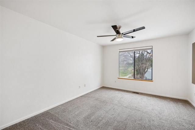 carpeted spare room featuring baseboards and a ceiling fan