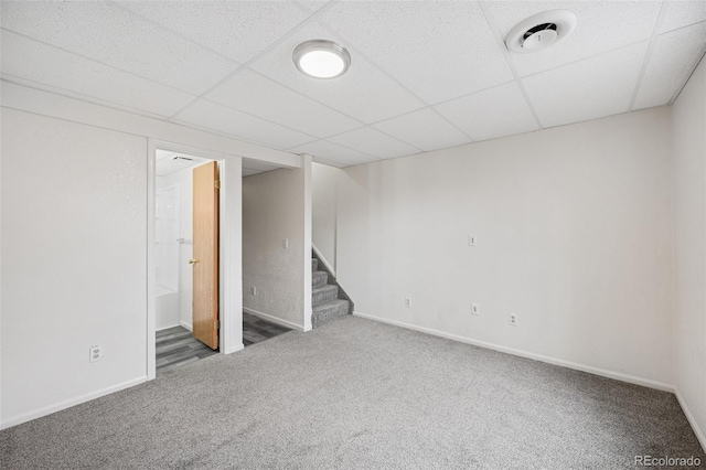 finished below grade area featuring baseboards, stairway, carpet, and a paneled ceiling