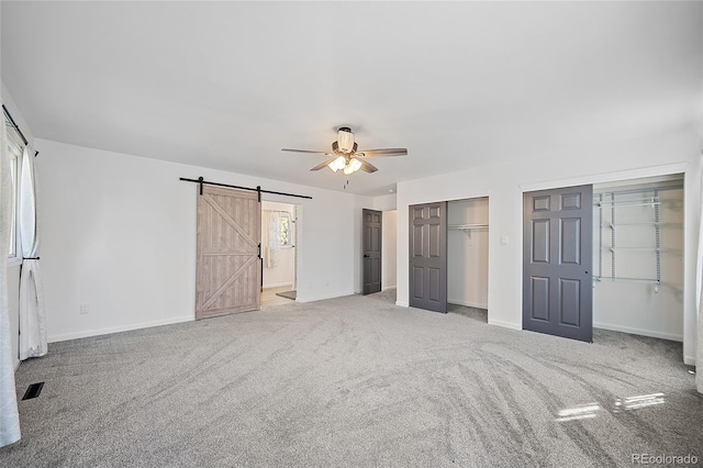 2020 Forest Ridge Dr, Colorado Springs, CO 80918 - unfurnished bedroom featuring two closets, ensuite bathroom, carpet, a barn door, and baseboards