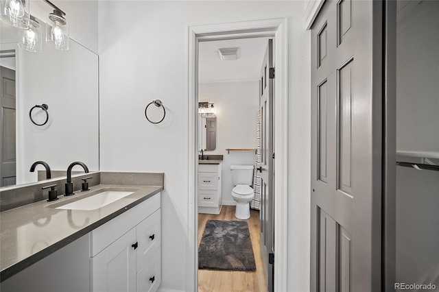 2020 Forest Ridge Dr, Colorado Springs, CO 80918 - bathroom featuring two vanities, visible vents, toilet, wood finished floors, and a sink