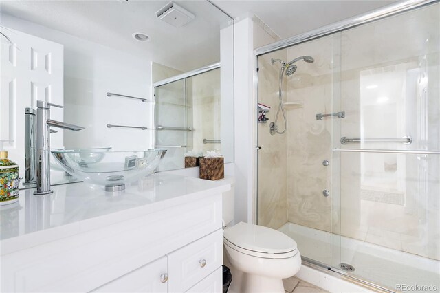 bathroom with vanity, a shower with shower door, toilet, and tile patterned flooring