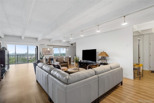 living room with light hardwood / wood-style flooring, a textured ceiling, beam ceiling, and rail lighting