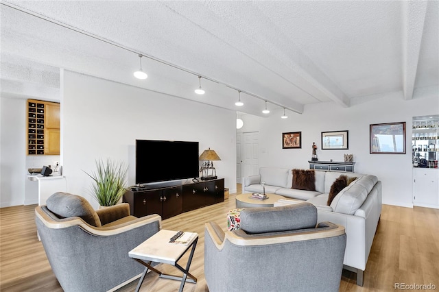 living room featuring beam ceiling, a textured ceiling, and light wood-type flooring