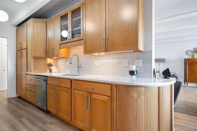 kitchen with tasteful backsplash, sink, and light wood-type flooring