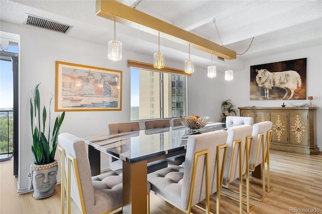 dining room featuring beamed ceiling, a textured ceiling, and hardwood / wood-style flooring