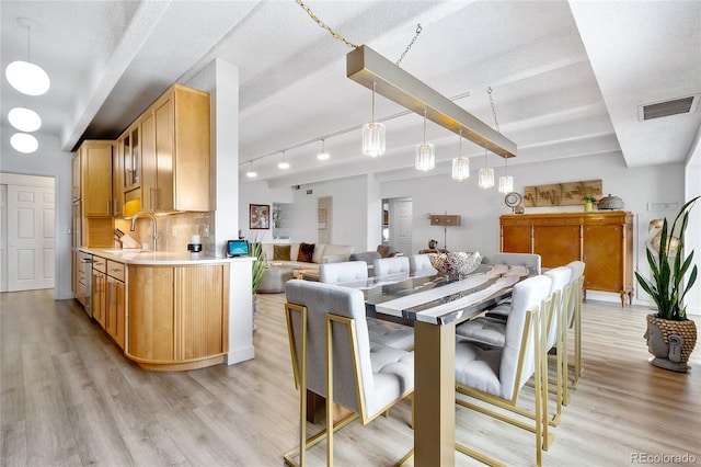 dining area with a textured ceiling, sink, and light wood-type flooring