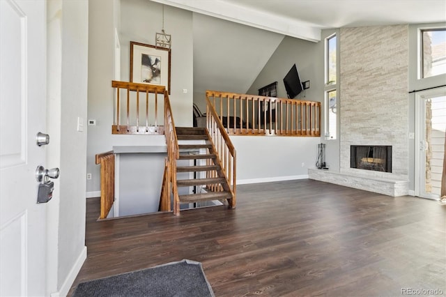 interior space featuring hardwood / wood-style floors, a stone fireplace, beamed ceiling, and high vaulted ceiling