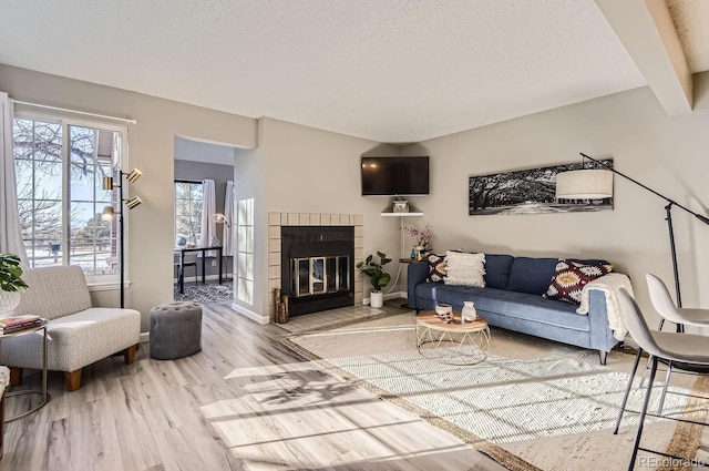 living room featuring light hardwood / wood-style floors, a brick fireplace, and a textured ceiling