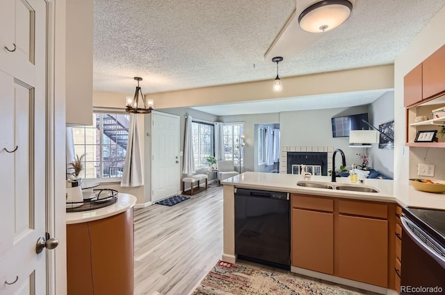 kitchen with sink, a textured ceiling, kitchen peninsula, black dishwasher, and light hardwood / wood-style floors