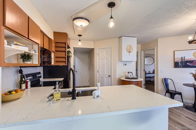 kitchen with sink, hanging light fixtures, range with electric stovetop, a textured ceiling, and kitchen peninsula