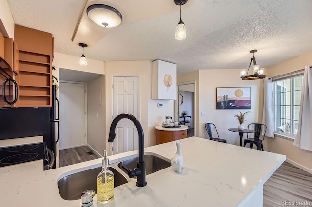 kitchen with light stone counters, hanging light fixtures, and kitchen peninsula