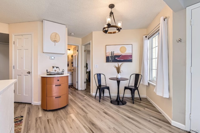 interior space with a notable chandelier, decorative light fixtures, light hardwood / wood-style flooring, and a textured ceiling