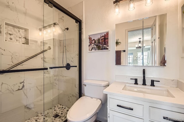 bathroom with toilet, vanity, an inviting chandelier, and a shower with shower door