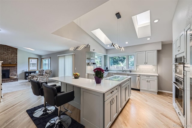 3743 W 103rd Dr, Westminster, CO 80031 - kitchen featuring stainless steel appliances, a skylight, vaulted ceiling, light countertops, and a center island