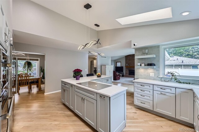 3743 W 103rd Dr, Westminster, CO 80031 - kitchen featuring gray cabinetry, a skylight, black electric stovetop, light wood-style flooring, and high vaulted ceiling