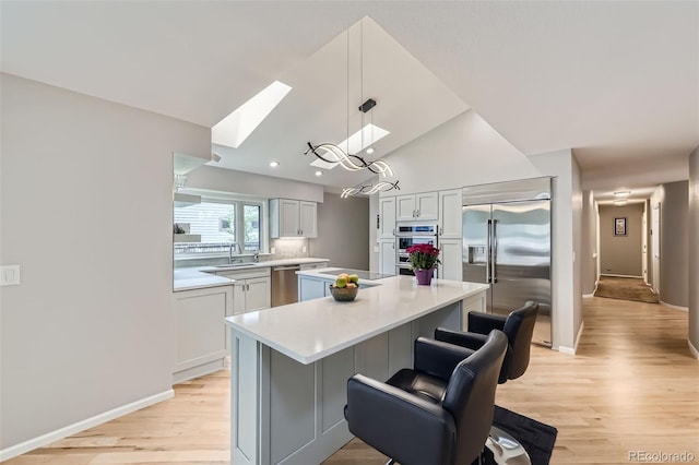 3743 W 103rd Dr, Westminster, CO 80031 - kitchen with stainless steel appliances, a center island, light countertops, light wood finished floors, and a skylight