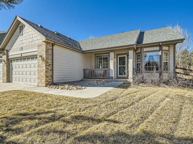 ranch-style house with a garage, roof with shingles, covered porch, a front lawn, and brick siding