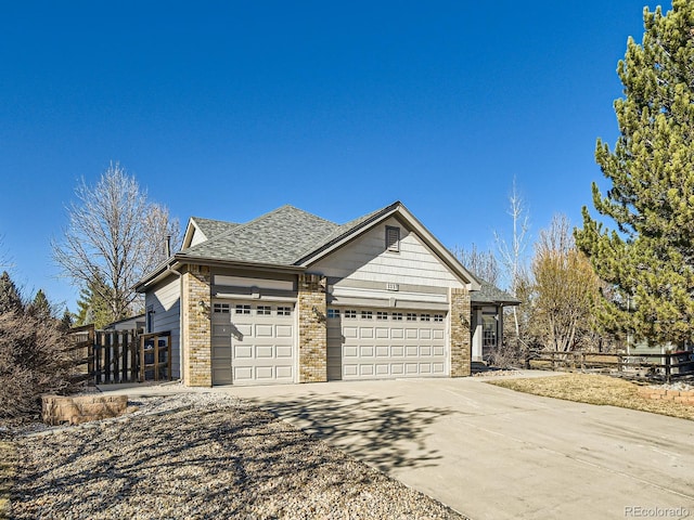 view of front of house featuring brick siding, roof with shingles, concrete driveway, fence, and a garage