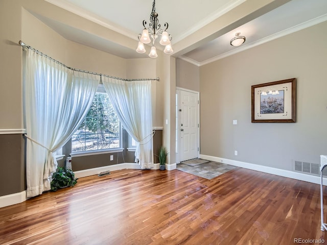 entryway with visible vents, baseboards, wood finished floors, and ornamental molding