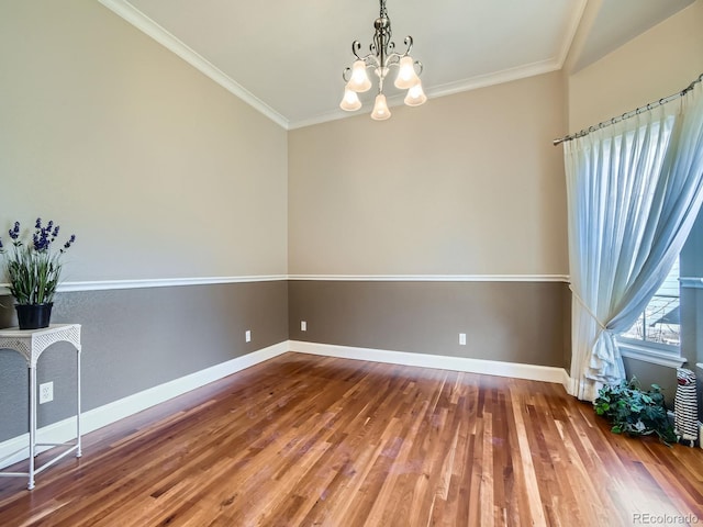 spare room featuring an inviting chandelier, baseboards, ornamental molding, and wood finished floors