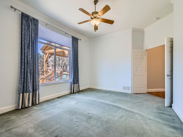 unfurnished room featuring baseboards, carpet flooring, visible vents, and crown molding