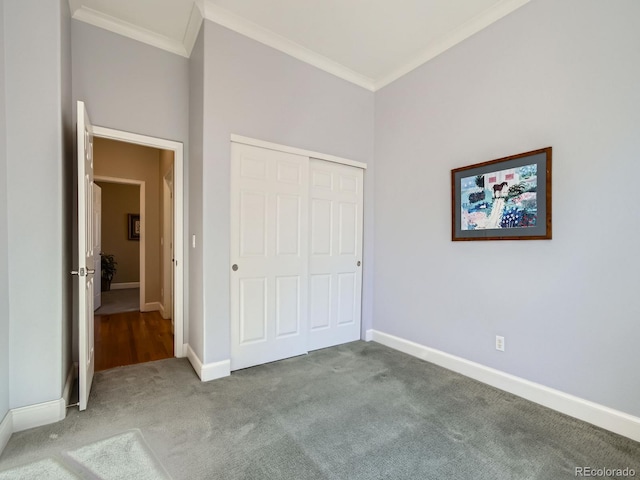 unfurnished bedroom with ornamental molding, a closet, carpet flooring, and baseboards