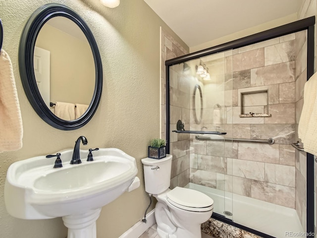 full bath featuring a textured wall, a stall shower, a sink, and toilet