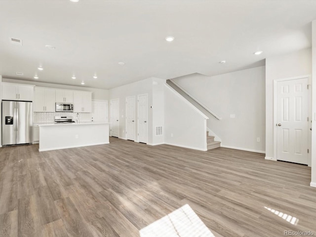 755 N Tibet St, Aurora, CO 80018 - unfurnished living room with recessed lighting, baseboards, light wood finished floors, and stairway