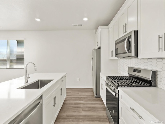 755 N Tibet St, Aurora, CO 80018 - kitchen featuring appliances with stainless steel finishes, a sink, light countertops, tasteful backsplash, and white cabinets