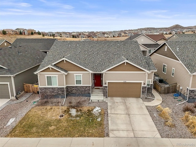 craftsman inspired home with a garage, stone siding, fence, and driveway